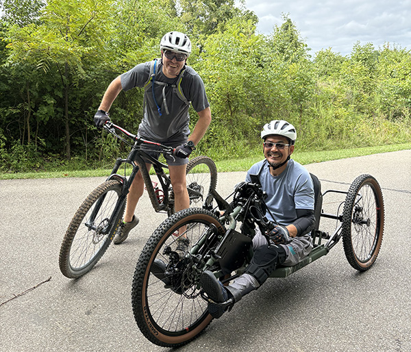 yoshi tomoyasu on a handcycle and another man on a bicycle