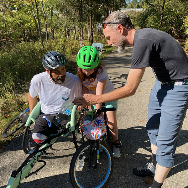 Steve Sullivan, director of Miami's Hefner Museum of Natural History, shows handcyclist Jacob Counts and his 8-year-old daughter, A.J., a tiny, camouflaged ambush bug, known for patiently waiting on flowers to prey on bees, flies, and other insects (photo by Margo Rutledge Kissell).