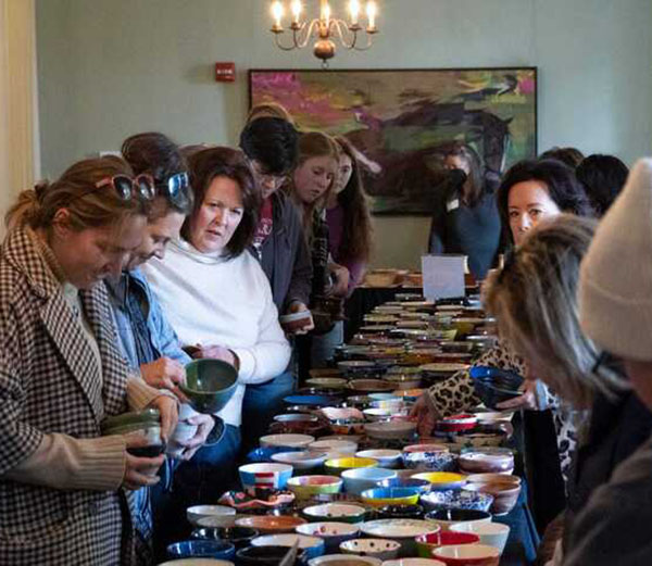 Oxford Empty Bowls event showing a long table filled with empty bowls and lines of people picking out bowls in the Oxford Community Art Cneter South Parlor 